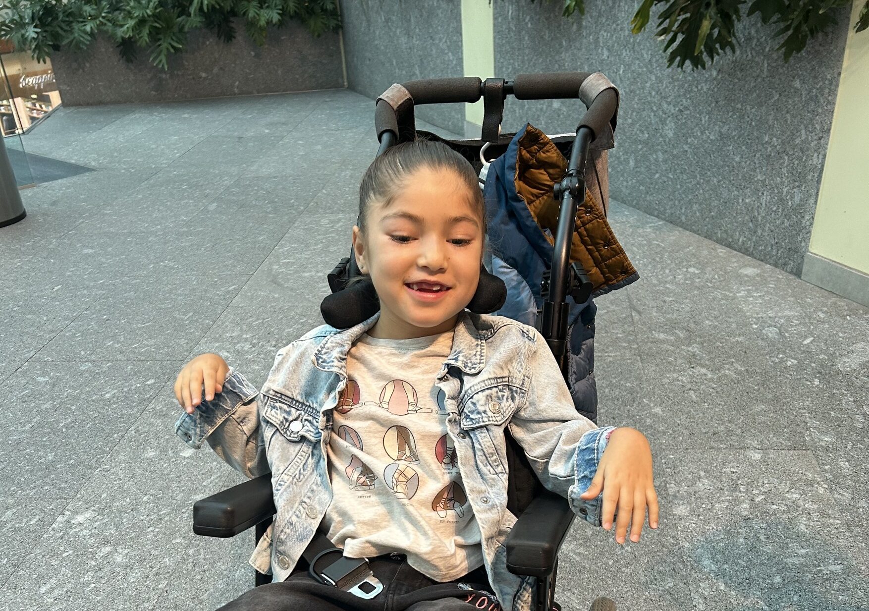 In this photo, a girl named Raquel poses from her wheelchair with a smile. To help her and others, consider launching a campaign to raise funds for research on mitochondrial disease.